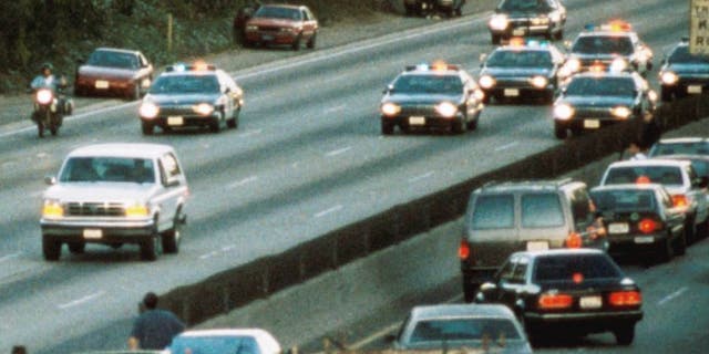 LOS ANGELES - JUNE 17: Motorists stop and wave as police cars pursue the Ford Bronco (white, R) driven by Al Cowlings, carrying fugitive murder suspect O.J. Simpson, on a 90-minute slow-speed car chase June 17, 1994 on the 405 freeway in Los Angeles, California. Simpson's friend Cowlings eventually drove Simpson home, with Simpson ducked under the back passenger seat, to Brentwood where he surrendered after a stand-off with police. (Photo by Jean-Marc Giboux/Liaison)