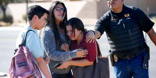 Students embrace after leaving campus, Friday, Feb. 12, 2016, in Glendale, Ariz.