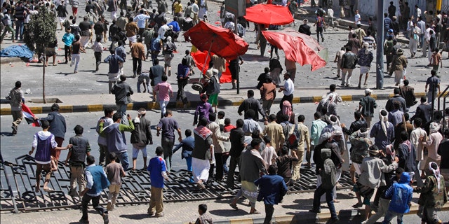 Feb. 17: Supporters of the Yemeni government, below, chase after anti-government demonstrators, top, during clashes in Sanaa, Yemen.