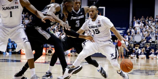 Xavier's Myles Davis (15) drives against Providence's Kris Dunn (3) and Kris Dunn, second from left, during the second half of an NCAA college basketball game Wednesday, Feb. 17, 2016, in Cincinnati. Xavier won 85-74. (AP Photo/John Minchillo)
