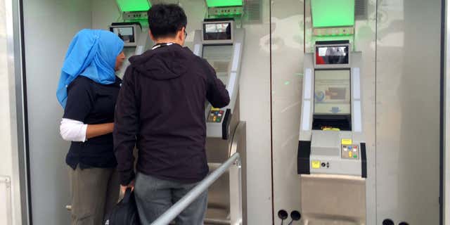 Feb. 18, 2016: A Customs and Border protection officer helps a man from China scan his documents while a camera records his iris and facial features to verify his documents while leaving San Diego on his way to Mexico.
