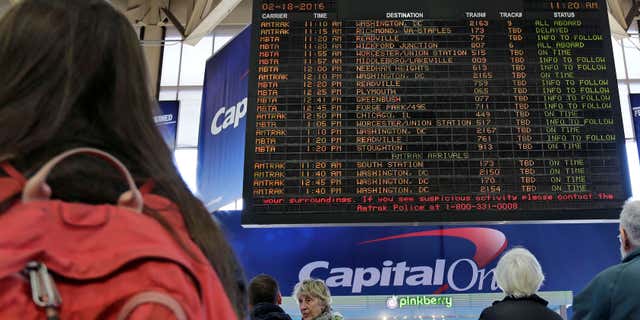 Feb. 18, 2016: With many delays and cancelations posted, travelers watch the train departure board at South Station in Boston.