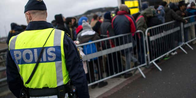 Nov. 19, 2015: A police officer keeps guard as migrants arrive at Hyllie station outside Malmo, Sweden.