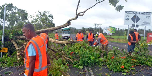 Road workers remove a fallen tree blocking a road near Lami, Fiji, Sunday, Feb. 21, 2016, after cyclone Winston ripped through the country.