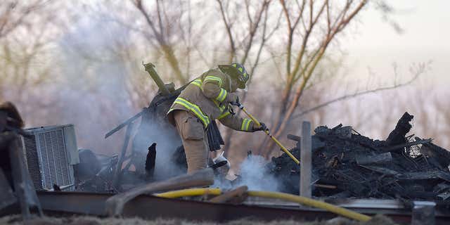 Feb. 20, 2016: A firefighter puts out a hot spot at the home 4170 Buena Vista Road in Edgerton, Mo.