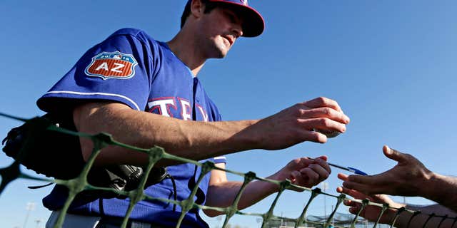 FILE - In this Feb. 21, 2016, file photo, Texas Rangers pitcher Cole Hamels signs autographs during spring training baseball practice, in Surprise, Ariz.