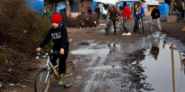 Feb. 25, 2016: A child rides his bicycle in a makeshift camp for migrants near Calais, France.