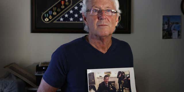 In this February 2017 photo, William Owens holds a photo of his youngest son Navy SEAL William "Ryan" Owens in Lauderdale by the Sea, Fla.
