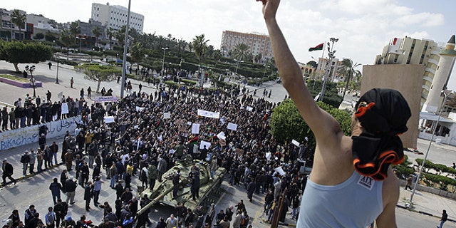 Feb. 27: Residents gather around a tank and an armed man on a rooftop flashes the victory sign, as foreign journalists arrive in Zawiya, 30 miles west of Tripoli, in Libya.