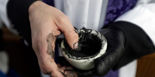 The Rev. Ethan Jewett, with Saint Clement's Episcopal Church, waits to place ash on worshippers' foreheads on Ash Wednesday in Philadelphia on Wednesday, Feb. 13, 2013. Ash Wednesday marks the beginning of Lent, a time when Christians prepare for Easter through acts of penitence and prayer. (AP Photo/Matt Rourke)