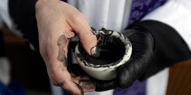 Reverend Ethan Jewett, with St. Clement's Episcopal Church, waits to place ashes on the foreheads of worshipers on Ash Wednesday in Philadelphia on Wednesday, Feb. 13, 2013. Ash Wednesday marks the start of Lent, a time when Christians are preparing for Easter until acts of penance and prayer. (AP Photo/Matt Rourke)