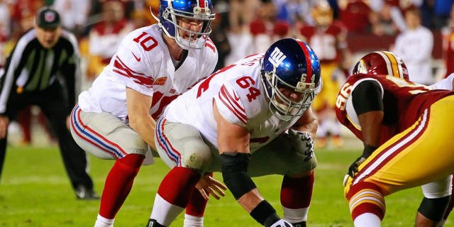 December 3, 2012; Landover, MD, USA; New York Giants quarterback Eli Manning (10) prepares to take a snap from Giants center David Baas (64) against the Washington Redskins at FedEx Field. Mandatory Credit: Geoff Burke-USA TODAY Sports