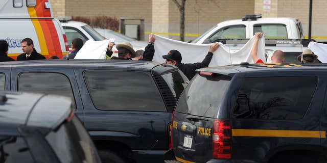In this photo taken on Thursday, Nov. 21, 2013, State police investigate near a vehicle in a supermarket parking lot in Pleasant Valley, N,Y., where 49-year-old pharmacist Abbas Lodhi and one of sons were found shot dead. Police say they later found the body of the man's other son at the family's nearby home. Police are continuing to search for the man's 43-year-old wife Sarwat Lodhi, who is missing and has unspecified injuries. They describe her as a victim in the case. (AP Photo/The Journal, Darryl Bautista) NO SALES. MIDDLETOWN OUT, KINGSTON OUT.