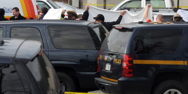 In this photo taken on Thursday, Nov. 21, 2013, State police investigate near a vehicle in a supermarket parking lot in Pleasant Valley, N,Y., where 49-year-old pharmacist Abbas Lodhi and one of sons were found shot dead. Police say they later found the body of the man's other son at the family's nearby home. Police are continuing to search for the man's 43-year-old wife Sarwat Lodhi, who is missing and has unspecified injuries. They describe her as a victim in the case. (AP Photo/The Journal, Darryl Bautista) NO SALES. MIDDLETOWN OUT, KINGSTON OUT.