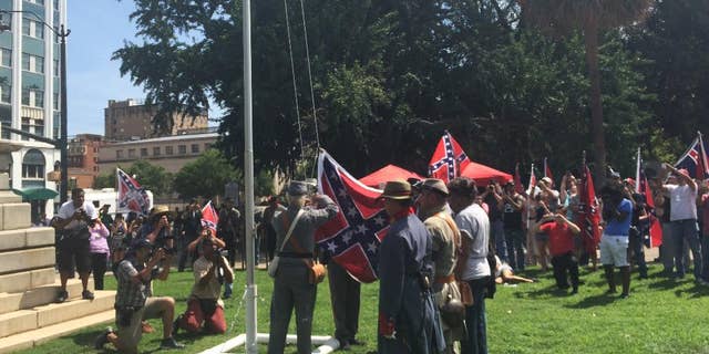 Supporters of the Confederate flag raise it on a temporary flagpole on the grounds of the Statehouse in Columbia, S.C., at a rally on Sunday, July 10, 2016. Counter-protesters showed up but the event was peaceful. (AP Photo/Meg Kinnard)