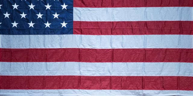 A man sticks his head out from under a large American flag as Democratic presidential candidate Hillary Clinton finishes a rally at Miami Dade College in Miami, Tuesday, Oct. 11, 2016. (AP Photo/Andrew Harnik)