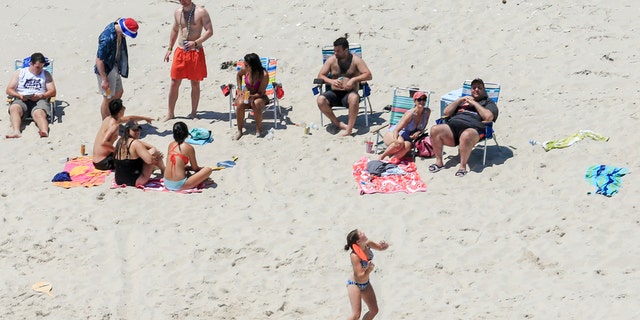 In this Sunday, July 2, 2017, photo, New Jersey Gov. Chris Christie, right, uses the beach with his family and friends at the governor's summer house at Island Beach State Park in New Jersey. Christie is defending his use of the beach, closed to the public during New Jersey's government shutdown, saying he had previously announced his vacation plans and the media had simply "caught a politician keeping his word." (Andrew Mills/NJ Advance Media via AP)