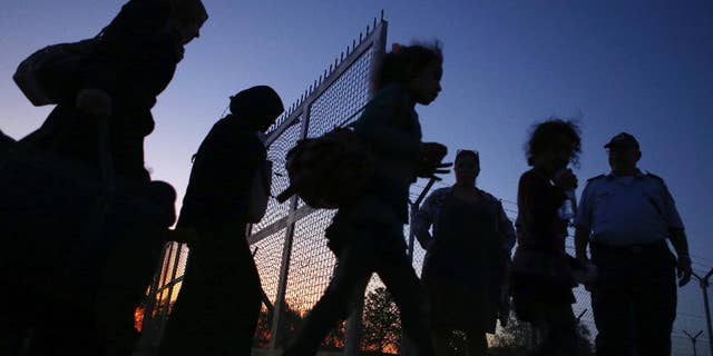 Migrants from Syria walk into a refugee camp in Kokkinotrimithia village outside the capital Nicosia, Cyprus, Friday, Oct. 21, 2016. A Cyprus police spokesman says a boat with 83 people aboard including 37 children has been towed to a harbor on the east Mediterranean island's northwestern coast. (AP Photo/Petros Karadjias)