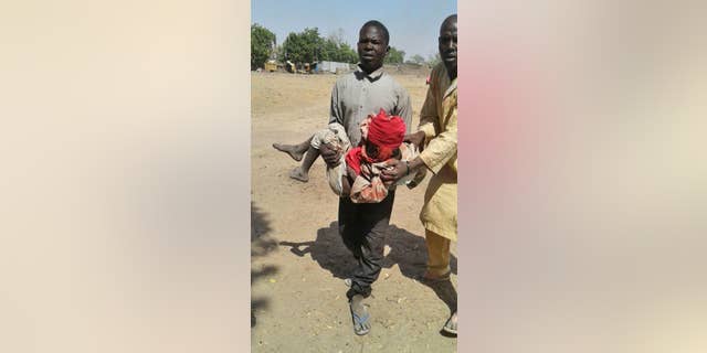 A man carries an injured child following a military airstrike at a camp for displaced people in Rann, Nigeria, Tuesday, Jan. 17, 2017. (Medecins Sans Frontieres (MSF) via AP)