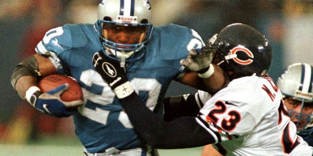 PONTIAC, : The Detroit Lions' Barry Sanders (L) brushes off Chicago Bears safety Marty Carter (R) on his way to the end zone for a touchdown in the third quarter, 27 November, at the Silverdome in Pontiac, MI. On the play, Sanders passed the 100-yard mark in a game for the 11th straight time tieing the NFL record held by Marcus Allen. The Lions beat the Bears 55-20. AFP PHOTO Matt CAMPBELL (Photo credit should read MATT CAMPBELL/AFP/Getty Images)