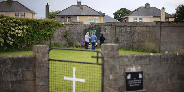 FILE In this June 7, 2014 file photo members of the public at the site of a mass grave for children who died in the Tuam mother and baby home, in Tuam, County Galway.