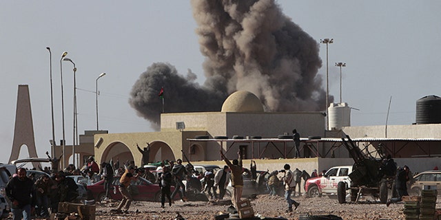 March 7: Anti-Qaddafirebels run away as smoke rises following an air strike by Libyan warplanes near a checkpoint in the oil town of Ras Lanouf, eastern Libya.