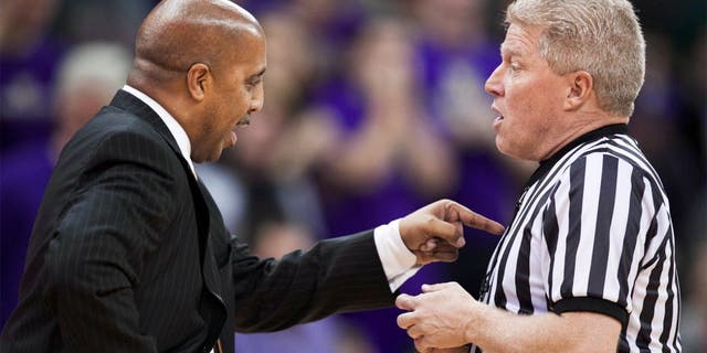 Washington head coach Lorenzo Romar, left, disputes a call with an official in the second half of an NCAA college basketball game against UCLA, Thursday March 6, 2014, in Seattle. UCLA won 91-82. (AP Photo/Stephen Brashear)
