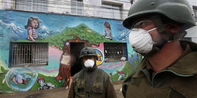 Soldiers wear masks as they patrol near a school in Talcahuano, Chile, Sunday, March 7, 2010. An 8.8-magnitude earthquake struck central Chile on Feb. 27, causing widespread damage. (AP Photo/Silvia Izquierdo)