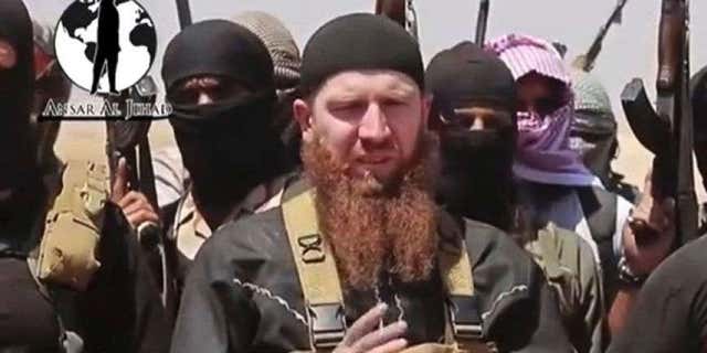 junio 28, 2014: This image made from undated video posted on a social media account frequently used for communications by the ISIS, which has been verified and is consistent with other AP reporting, shows Abu Umar al-Shishani standing next to the group's spokesman among a group of fighters as they declare the elimination of the border between Iraq and Syria.