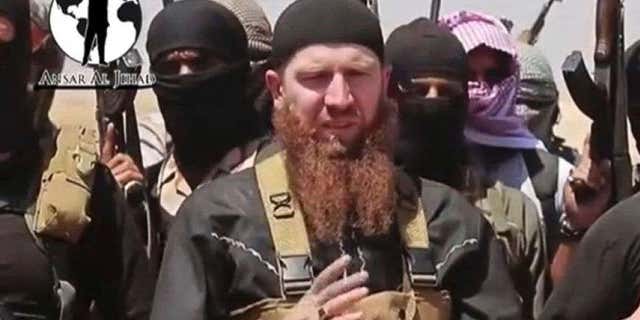 June 28, 2014: This image made from undated video posted on a social media account frequently used for communications by the ISIS, which has been verified and is consistent with other AP reporting, shows Abu Umar al-Shishani standing next to the group's spokesman among a group of fighters as they declare the elimination of the border between Iraq and Syria.