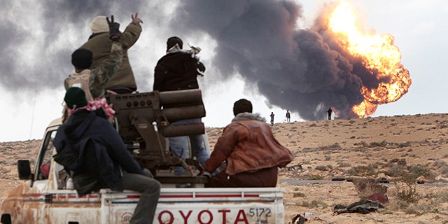 March 9: Anti-Qaddafi rebels ride on a truck with a multiple rocket launcher, as flames rises from a fuel storage facility that was attacked during fighting with pro-fighters, in Sedra, eastern Libya.