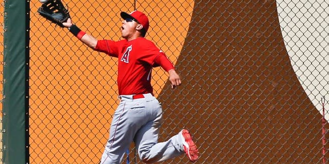 Los Angeles Angels left fielder Efren Navarro misplays the ball hit by Kansas City Royals' Alcides Escobar in the third inning of a spring training baseball game Saturday, March 14, 2015, in Surprise, Ariz. (AP Photo/Lenny Ignelzi)