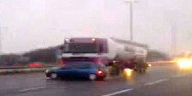 Truck driver appears unaware he is pushing a  Renault down a British highway at 60 mph.