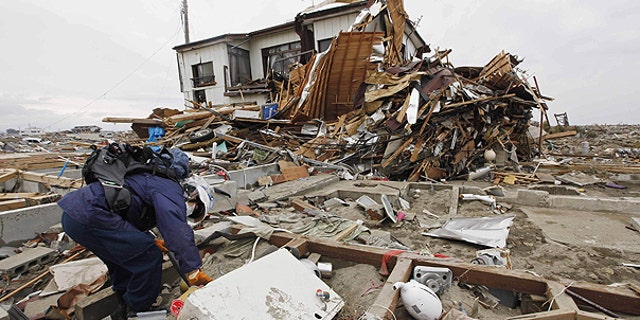 March 21: A rescue worker sifts through debris during a search in Natori, Miyagi Prefecture following the March 11 earthquake and tsunami that devastated the northeast coast of Japan.