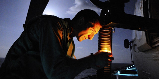 March 19: In this photo provided by the U.S. Navy, Naval Air Crewman 2nd Class Jordan Orr, assigned to Helicopter Sea Combat Squadron 22, checks the mount for a GAL-21 machine gun on a Sea Hawk helicopter on the flight deck of amphibious assault ship USS Kearsarge in preparation for operations against Libya in the Mediterranean Sea.