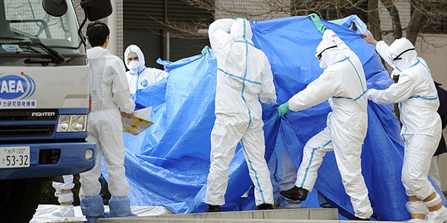 March 25: Workers, who stepped into radiation-contaminated water during Thursday's operation at the Fukushima Dai-ichi nuclear plant, are shielded with tarps before receiving decontamination treatment at a hospital in Fukushima, northeastern Japan.