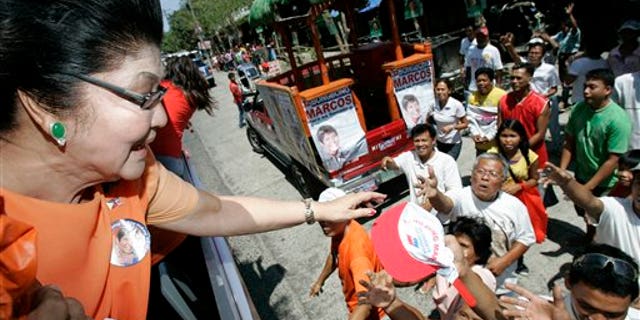 March 26: Imelda Marcos, left, widow of the late strongman Ferdinand Marcos, gives away caps during a campaign sortie in Batac, Ilocos Norte, northern Philippines. Marcos is running for a seat in the house of representatives along with her son, senatorial bet Ferdinand "Bongbong" Marcos Jr., and her daughter, Imee, a gubernatorial candidate in the Marcos's political stronghold.