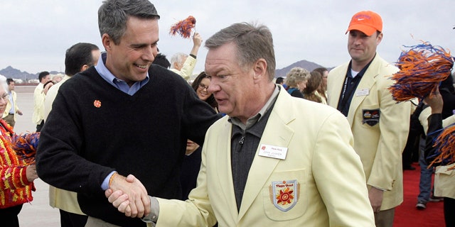 In this Dec. 28, 2009, file photo, Boise State coach Chris Petersen, left, is greeted by Fiesta Bowl president John Junker, right, after Petersen disembarked off a charter flight at Sky Harbor International Airport in Phoenix.