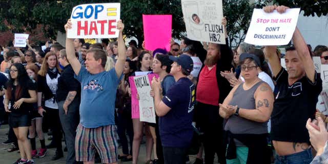 People protest outside the North Carolina Executive Mansion in Raleigh, N.C., Thursday, March 24, 2016. North Carolina legislators decided to rein in local governments by approving a bill Wednesday that prevents cities and counties from passing their own anti-discrimination rules.