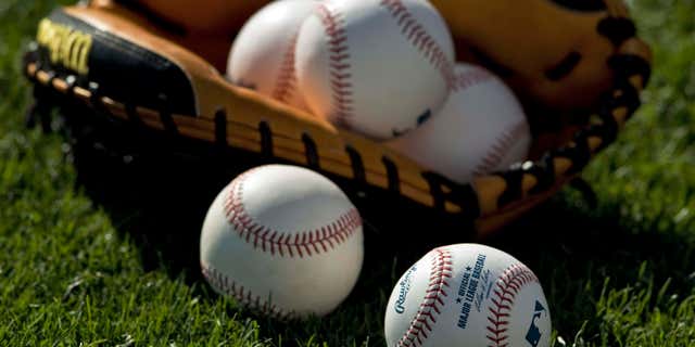 March 25, 2013: Baseballs and a catcher's mitt lie on the grass before a MLB spring training baseball game between the Boston Red Sox and Baltimore Orioles in Sarasota, Florida.