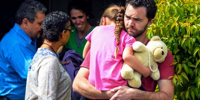 FILE - In this March 21, 2016 file photo, Rusty Page carries Lexi while Summer Page, in the background, cries as members of family services, left, arrive to take Lexi away from her foster family in Santa Clarita, Calif.