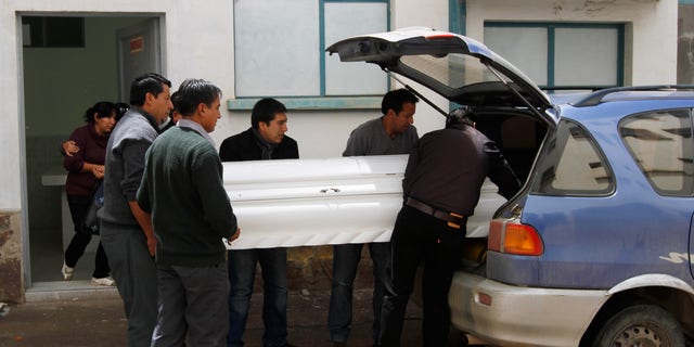 Relatives place the coffin containing the remains of Kevin Beltran Estrada, who died after an explosive went off during a soccer game, into a car in Oruro, Bolivia, Thursday, Feb. 21, 2013.  Twelve Corinthian soccer fans were arrested on suspicion of having caused the death of a 14-year-old San Jose soccer fan by launching an explosive device during a Copa Libertadores game between San Jose and Corinthians on Wednesday in the Bolivian city of Oruro, according to police. (AP Photo/Juan Karita)