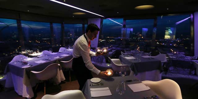 FILE- In this March 6, 2013 file photo, a waiter sets a candle on a table in a restaurant at the Zizkov television tower in Prague, Czech Republic. The Czech Republic has launched a new system to increase tax revenue by requiring bars and restaurants to report their sales online. (AP Photo/Petr David Josek)