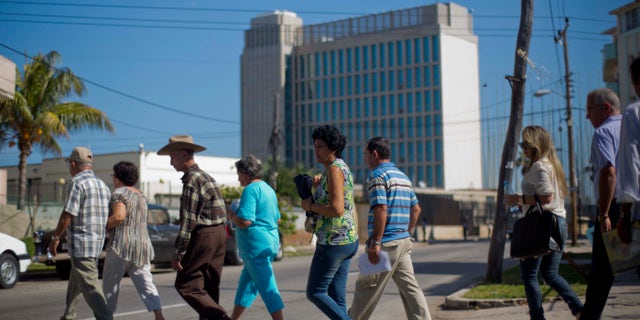 In this photo taken Jan. 13, 2014, people walk in line while entering the U.S. Interests Section to apply for U.S. travel visas in Havana, Cuba. Cubans are taking advantage of a travel reform that went into effect a year ago, when the government scrapped an exit visa requirement that for five decades had made it difficult for most islanders to go abroad. Now they are traveling in record numbers. (AP Photo/Ramon Espinosa)