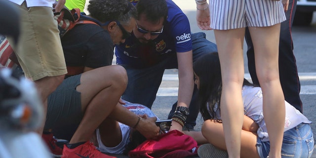 An injured person is treated in Barcelona, Spain, Thursday, Aug. 17, 2017 after a white van jumped the sidewalk in the historic Las Ramblas district, crashing into a summer crowd of residents and tourists and injuring several people, police said. (AP Photo/Oriol Duran)