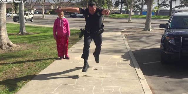 In this Wednesday, March 30, 2016 still frame from video provided by the Huntington Beach, Calif., Police Department, Officer Zach Pricer shows an 11-year-old homeless girl how to hopscotch on a street in Huntington Beach, Calif.