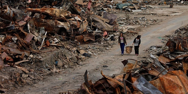 April 7: Two women walk past debris in an area devastated by the March 11 earthquake and tsunami in Ishinomaki, Miyagi Prefecture, northern Japan.