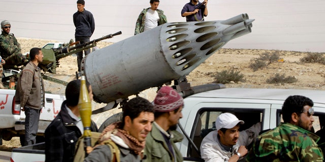 April 6: Libyan rebel fighters look in the distance as black smoke rises on the skyline, unseen, next to a pickup truck on which the rebels have mounted a rocket launcher, normally mounted on a helicopter, near Brega, Libya.