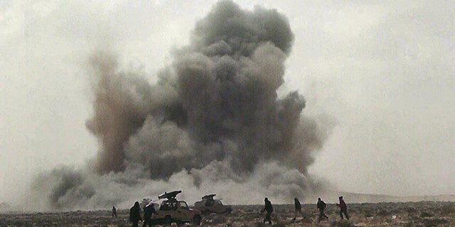FILE: In this April 7, 2011, image made from television, a dust cloud is seen following the explosion of a missile, outside the strategic oil port of Brega, Libya.