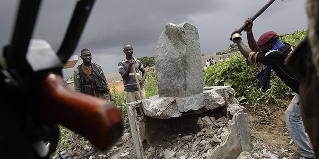 April 10: A soldier allied with Alassane Ouattara knocks down a monument believed to mystically provide strength and support to Laurent Gbagbo, in the Youpougon neighborhood of Abidjan, Ivory Coast.